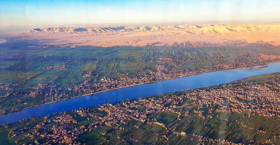The city of Luxor, crossed and sustained by the Nile in Egypt. Beyond the hills stretches the vast expanse of the Sahara Desert. CK-TravelPhotos / Shutterstock